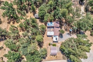 An aerial view of a property with a main building, a smaller structure, and a fenced area.