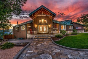 Stately entrance with a large door and welcoming light fixture, set amidst a beautifully maintained lawn and stone pathway.