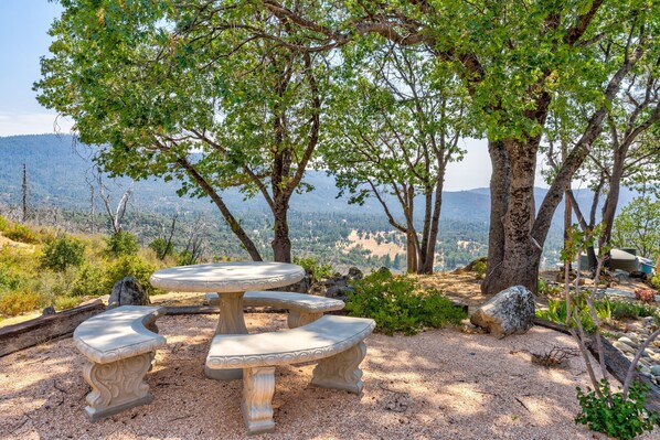 Enjoy a serene outdoor setting with a stone picnic table and benches amidst a picturesque mountainous landscape.