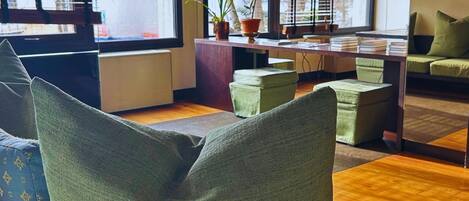 A modern living room with green upholstered furniture, a wooden coffee table, and a potted plant.