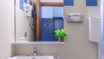 A bathroom with a sink, mirror, towel rack, and a potted plant.
