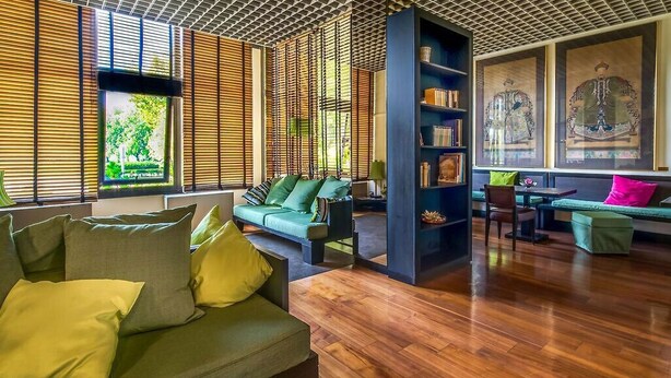 Un salon moderne avec un plancher en bois, des canapés verts et une bibliothèque.