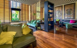 Ein modernes Wohnzimmer mit Holzboden, grünen Sofas und einem Bücherregal.
