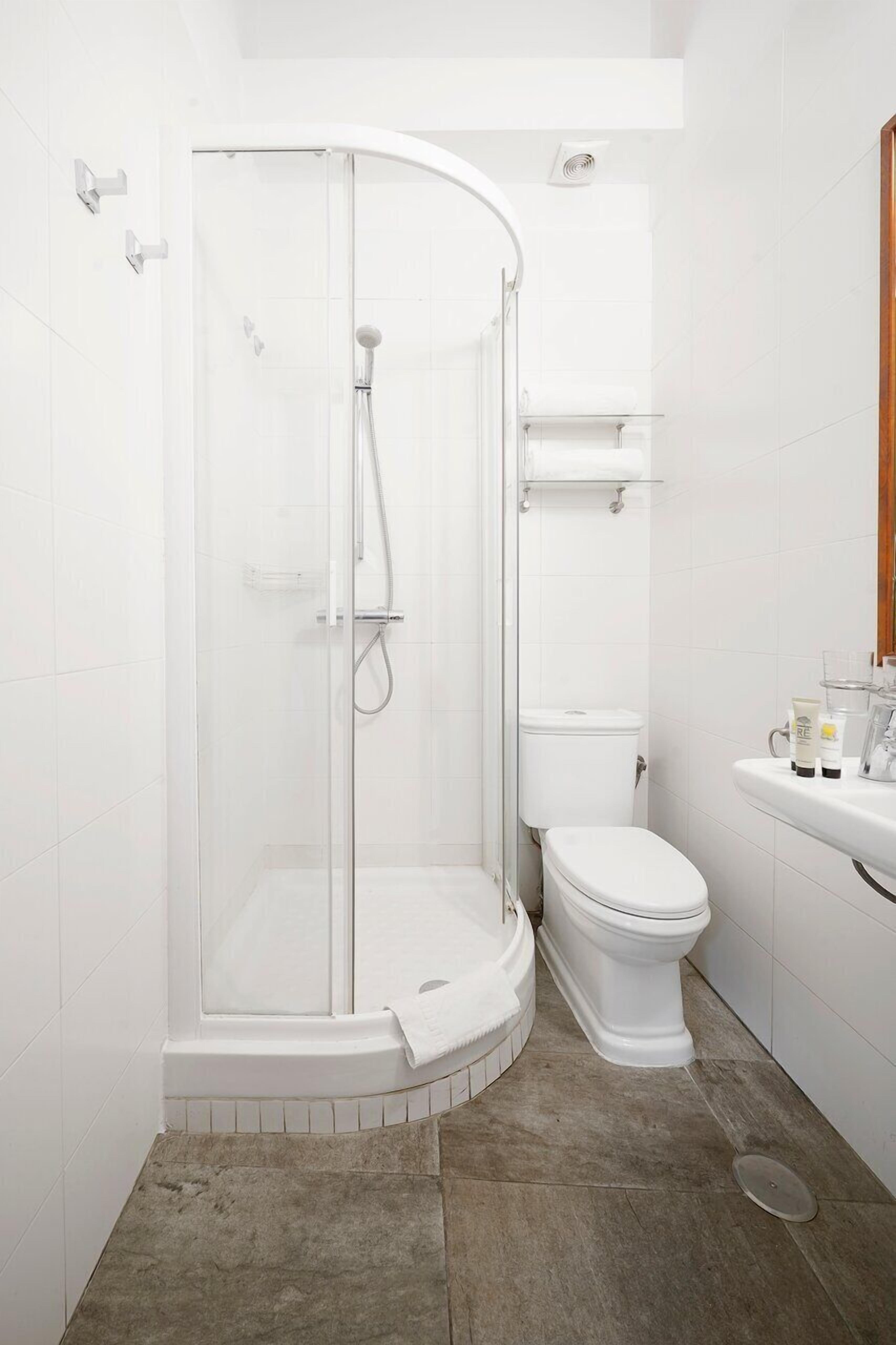 Een badkamer met een douche met glazen wand, een toilet en een wastafel.
