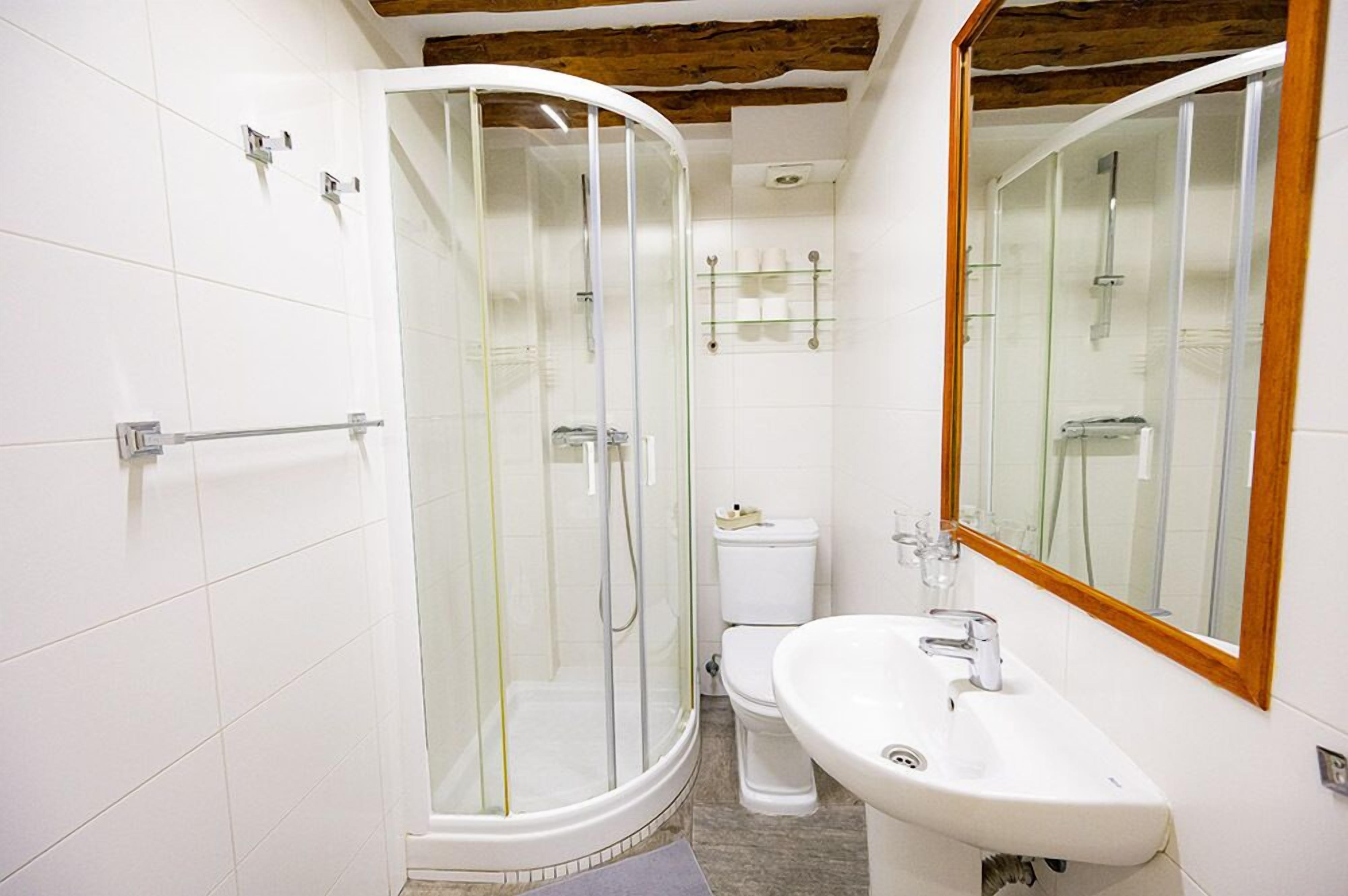 A bathroom with a glass-enclosed shower, a white sink, and a toilet.
