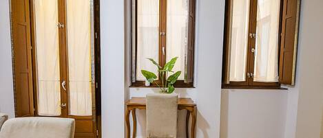 Una habitación con piso de madera, un escritorio con una silla y una planta en maceta.