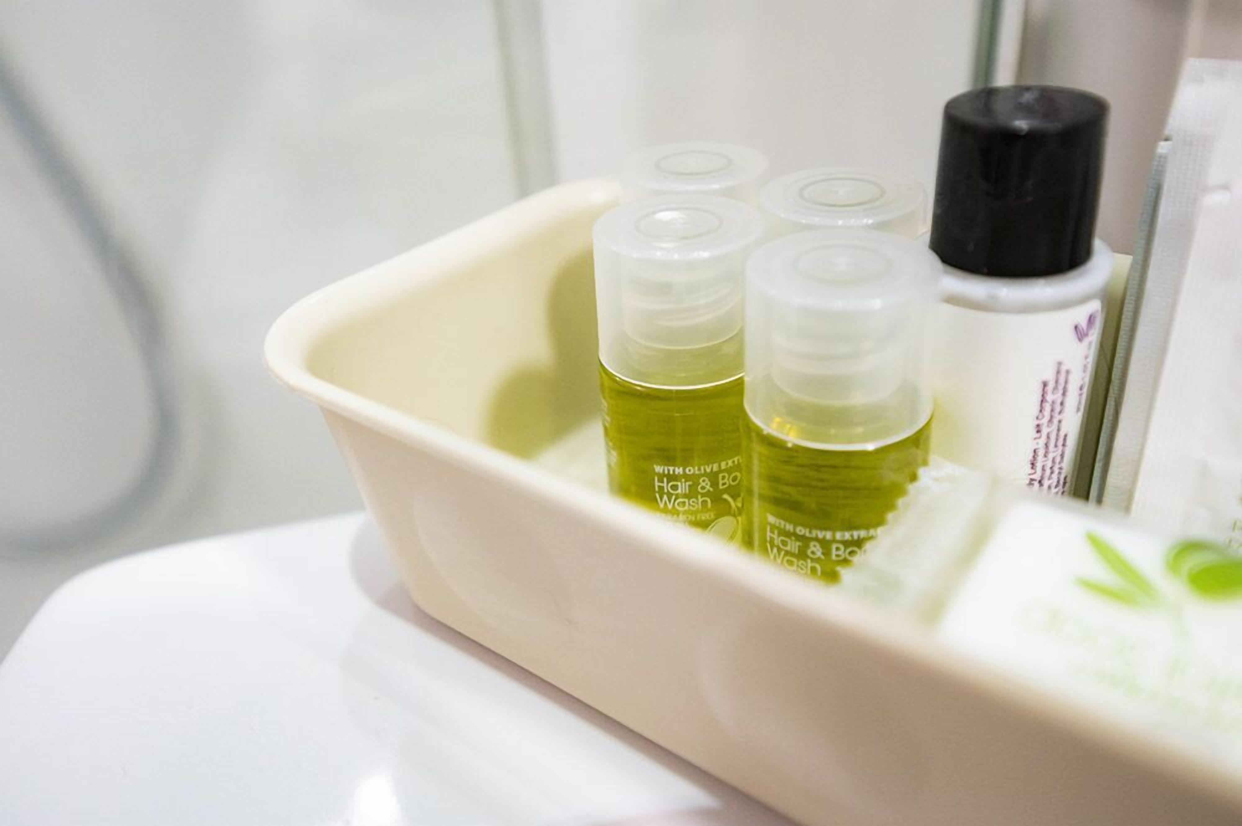 Un lavabo in bagno con tre flaconi di shampoo e bagnoschiuma.