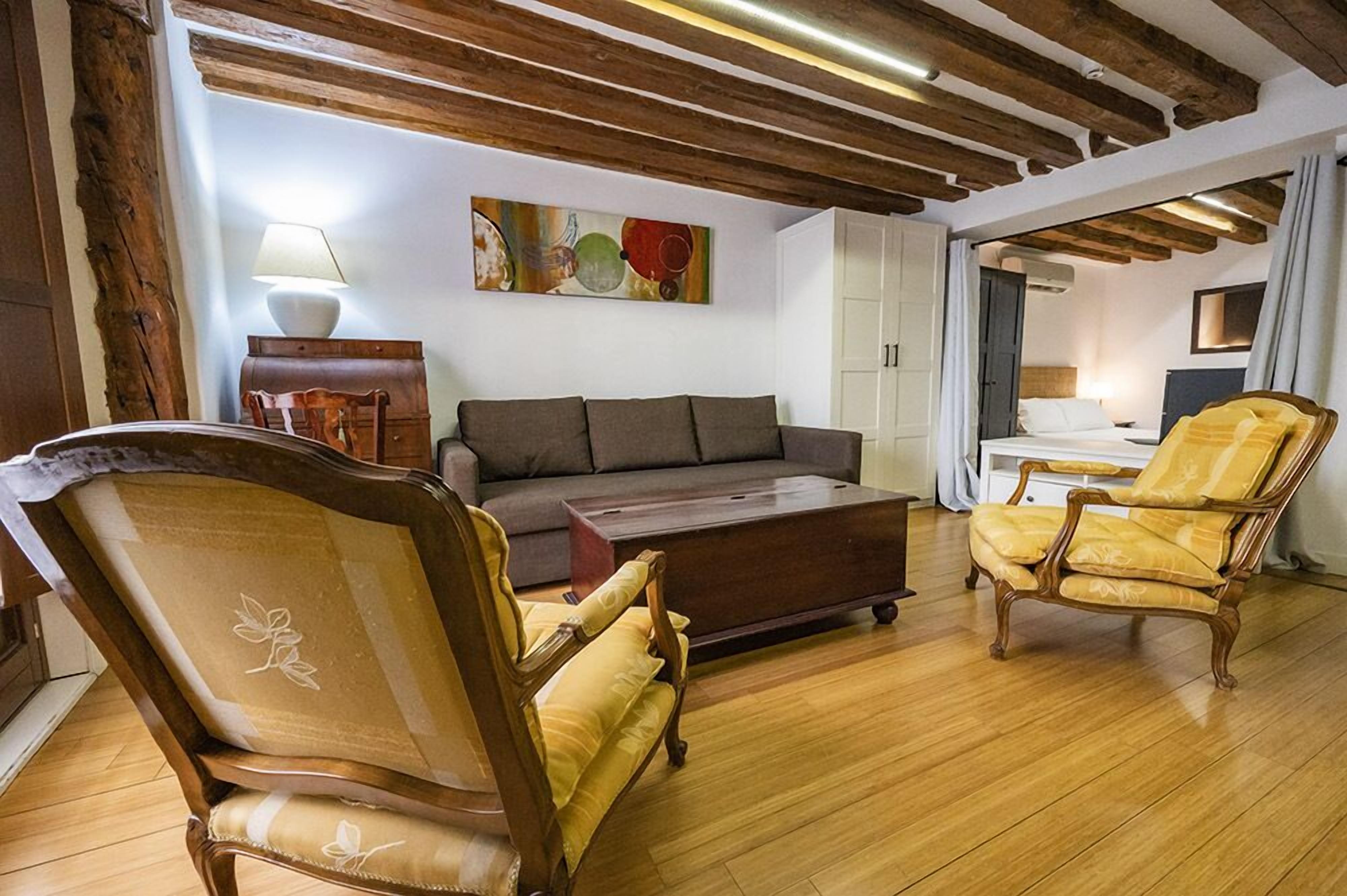 Una sala de estar con un sofá, dos sillones, una mesa de centro y un cuadro en la pared.