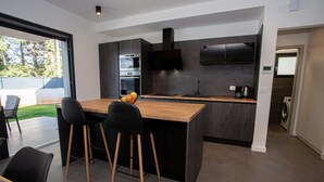 Une cuisine moderne avec un îlot central, des chaises noires et un four encastré.