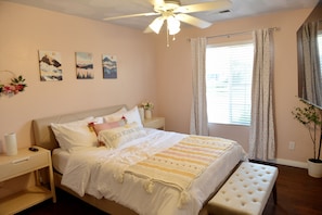 A bedroom with a bed, bedside tables, a ceiling fan, a window with curtains, and wall art. - Spacious 4BD Home w EV charger near Sequoia Ntl Pk (Visalia)