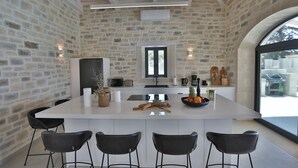 Una cocina moderna con una isla grande, taburetes de bar y un fondo de pared de piedra.