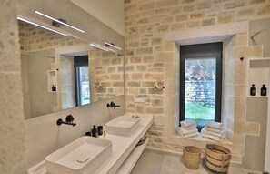 A modern bathroom with two sinks, a large mirror, and a stone wall. - new natural stone villa with large pool and great sea views (Prines)