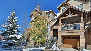 A multi-story building with a stone facade, a wooden balcony, and a garage.