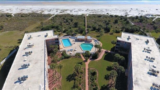 An aerial view of a resort with two swimming pools, a beach, and a mountainous backdrop. - Beach and Tennis 118 - Updated Ground floor unit with screen porch and easy (St. Augustine Beach)