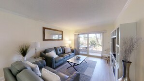 A modern living room with a sofa, coffee table, and a large mirror. - Beach and Tennis 118 - Updated Ground floor unit with screen porch and easy (St. Augustine Beach)
