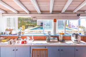 A kitchen with a view of a pool, a coffee maker, and a kettle.