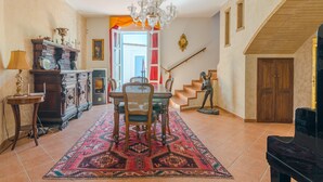 A dining area with a chandelier, a piano, and a staircase leading to another level. - Villa 'Casa Vacanza Cristina' with Private Pool, Terrace, and Wi-Fi (Plemmirio)
