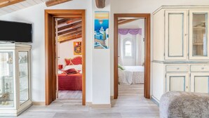 A room with a television, a bed with red bedding, a painting, and a cabinet. - Villa 'Casa Vacanza Cristina' with Private Pool, Terrace, and Wi-Fi (Plemmirio)
