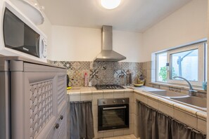 A kitchen with a microwave, gas stove, oven, and a window with a view.
