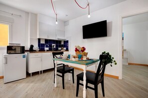 Une cuisine moderne avec des meubles blancs, un four à micro-ondes, un évier et un coin repas comprenant une table et des chaises.