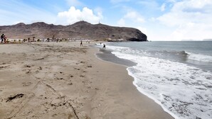 A beach with a mountain in the background, sandy shore, and footprints. - Vacation Home 'Holidays Maxorata Relax' close to the Beach with Wi-Fi (Gran Tarajal)