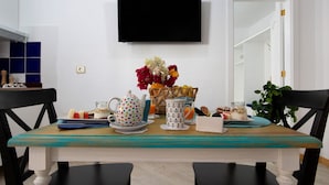 A dining table with a teal tablecloth, a television mounted on the wall, and a variety of tableware and decorations. - Vacation Home 'Holidays Maxorata Relax' close to the Beach with Wi-Fi (Gran Tarajal)