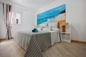 A bedroom with a bed, a painting of a beach scene, a window, and a curtain. - Vacation Home 'Holidays Maxorata Relax' close to the Beach with Wi-Fi (Gran Tarajal)