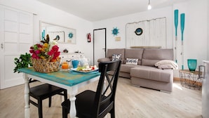 A dining area with a table set for two, a sofa, and decorative wall art. - Vacation Home 'Holidays Maxorata Relax' close to the Beach with Wi-Fi (Gran Tarajal)