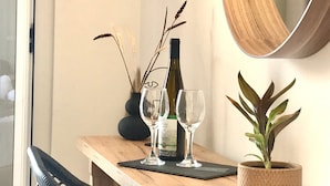A wooden table with a wine bottle and two glasses, a potted plant, and a mirror on a wall.
