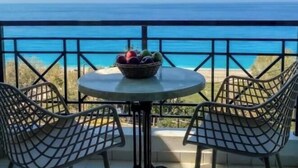 A balcony with a table and chairs, a bowl of fruit, and a view of the ocean. - Apartment in a Hotel 'Sunset Premium Studio 1' with Sea View, Shared Pool, & Wi-Fi (Lefkada)