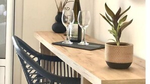 A wooden table with a mirror, a bottle, two glasses, and a potted plant. - Apartment in a Hotel 'Sunset Premium Studio 1' with Sea View, Shared Pool, & Wi-Fi (Lefkada)