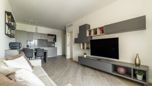 A modern living room with a sofa, TV, and entertainment unit. - GuestHost - Trastevere Modern Flat with Terrace (Roma)