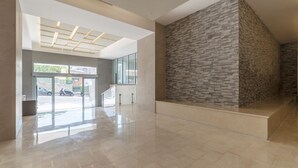 A spacious lobby with a modern design, a stone accent wall, and a glass entrance leading outside. - GuestHost - Trastevere Modern Flat with Terrace (Roma)