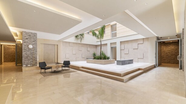 A spacious indoor area with a high ceiling, a central seating area with a coffee table, and a staircase leading to an upper level. - GuestHost - Trastevere Modern Flat with Terrace (Roma)
