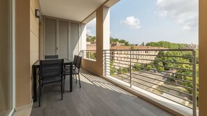 A balcony with a table and chairs, a view of buildings, and a railing. - GuestHost - Trastevere Modern Flat with Terrace (Roma)