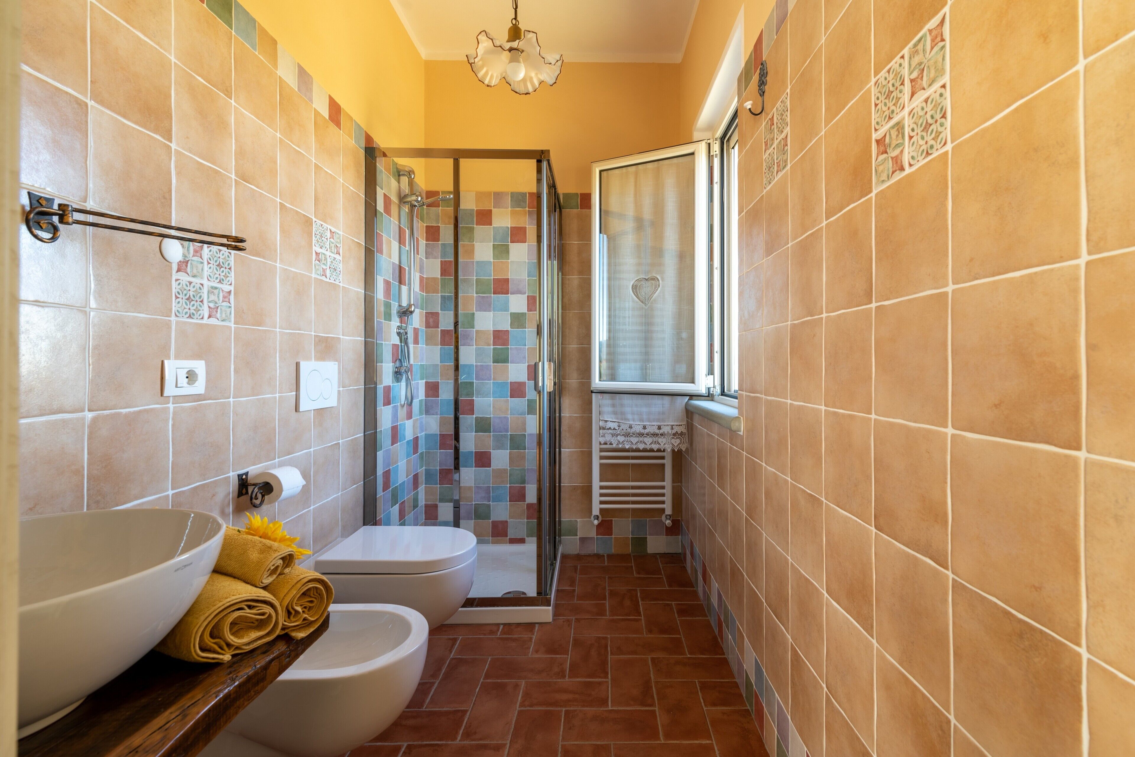 Ein Badezimmer mit Dusche, Toilette und Waschbecken, mit Fliesenboden und -wänden.