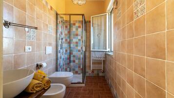 Ein Badezimmer mit Dusche, Toilette und Waschbecken, mit Fliesenboden und -wänden.