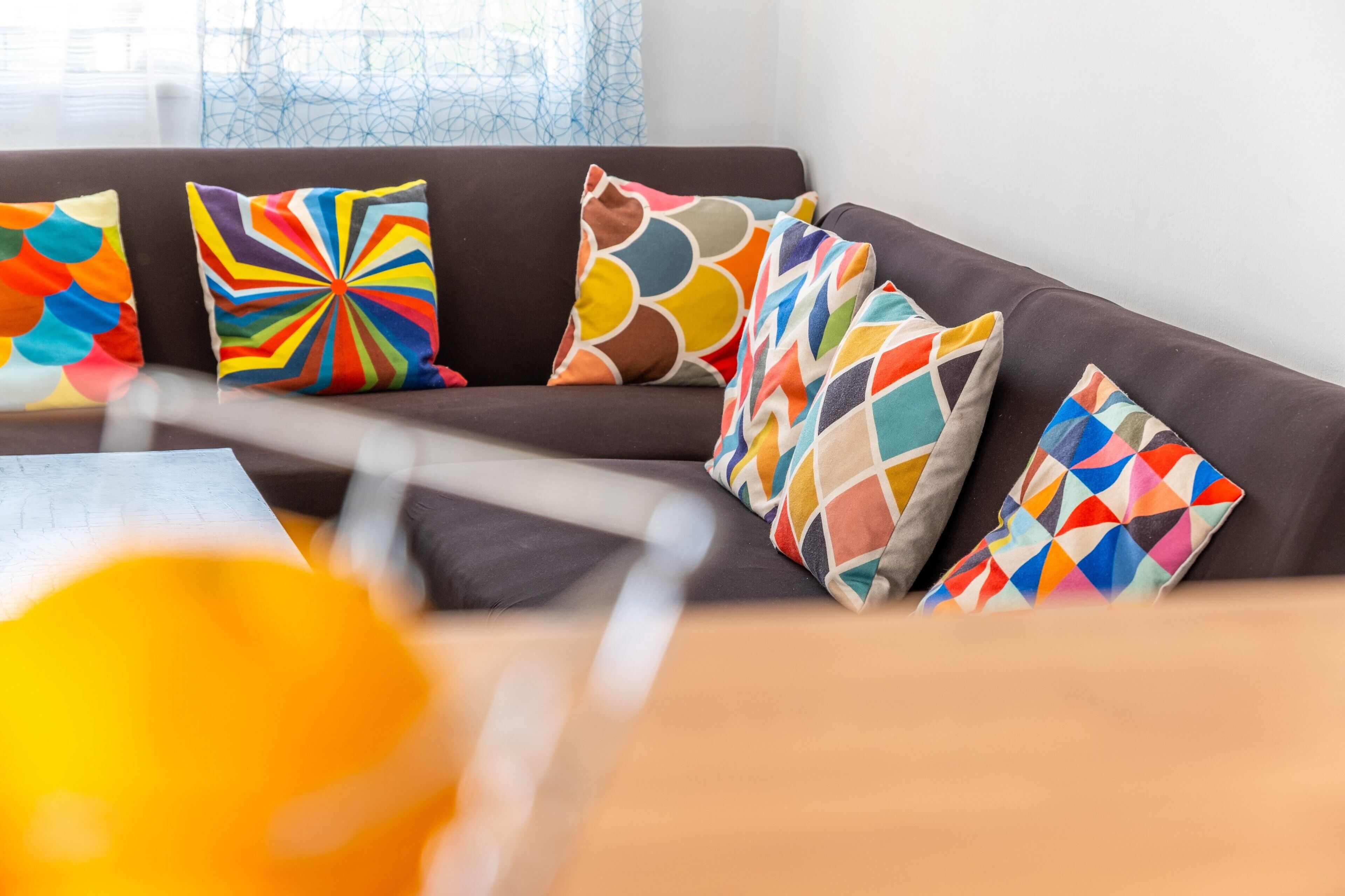 A modern living room with a dark-colored sofa and colorful geometric-patterned cushions.