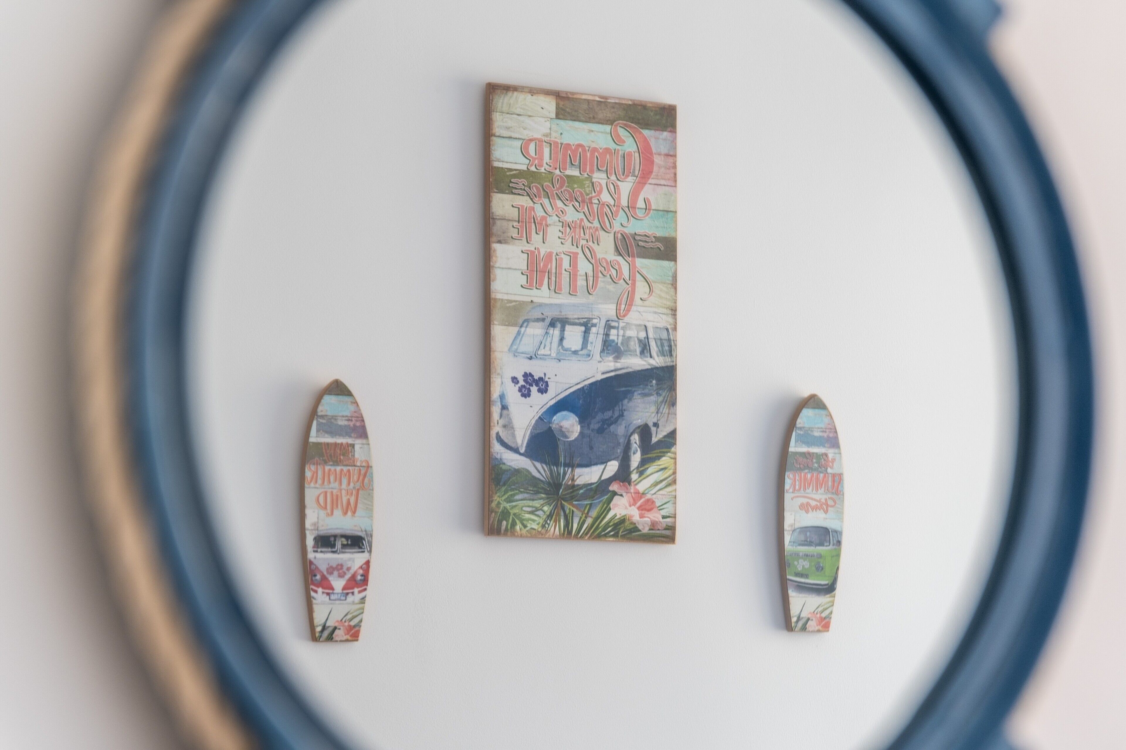 A wall with a framed artwork and two surfboards.