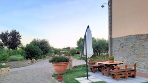 Un patio con mesa y sillas, rodeado de un muro de piedra y follaje.