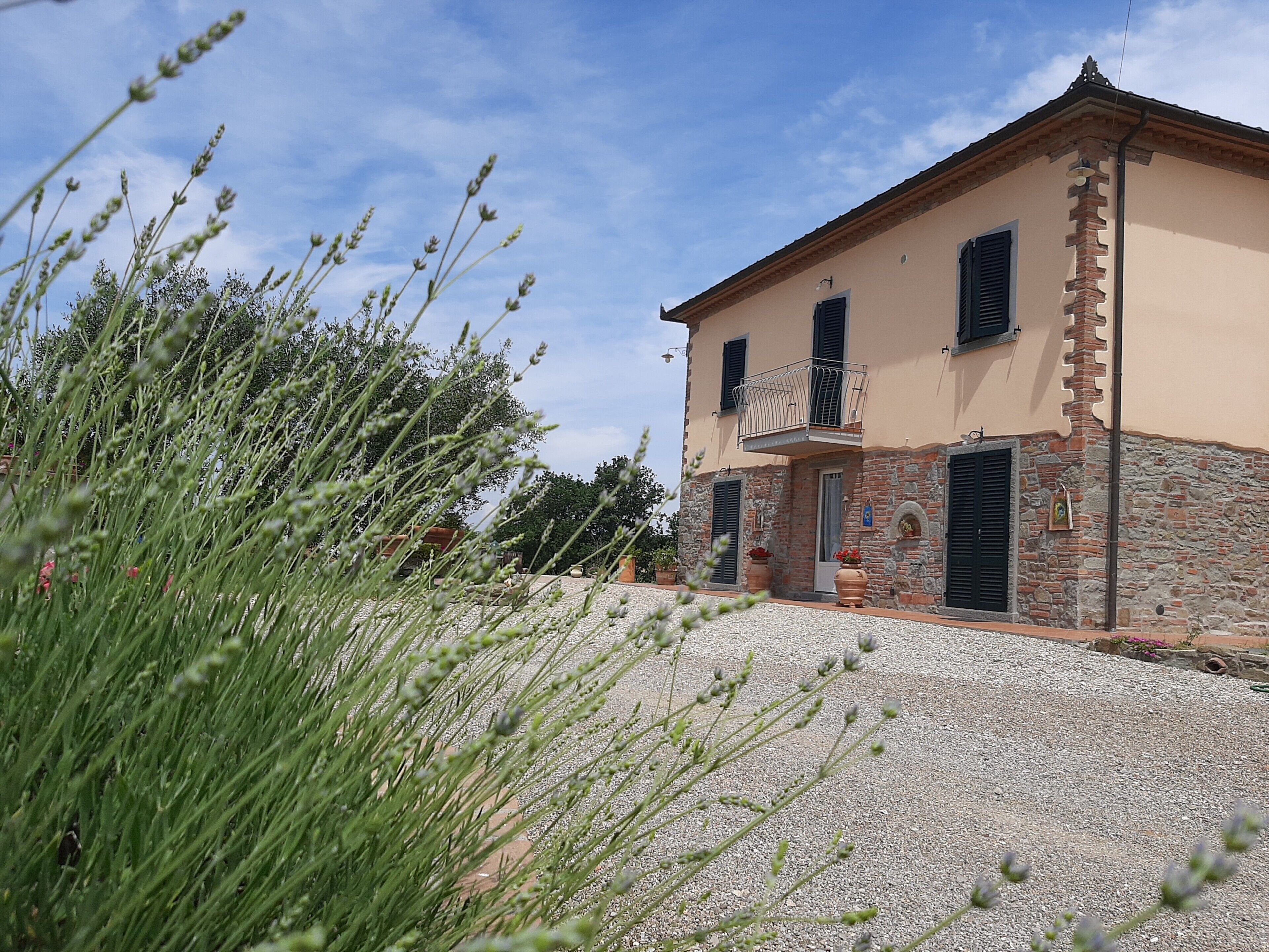 A two-story building with a stone facade, a balcony, and a gravel driveway.