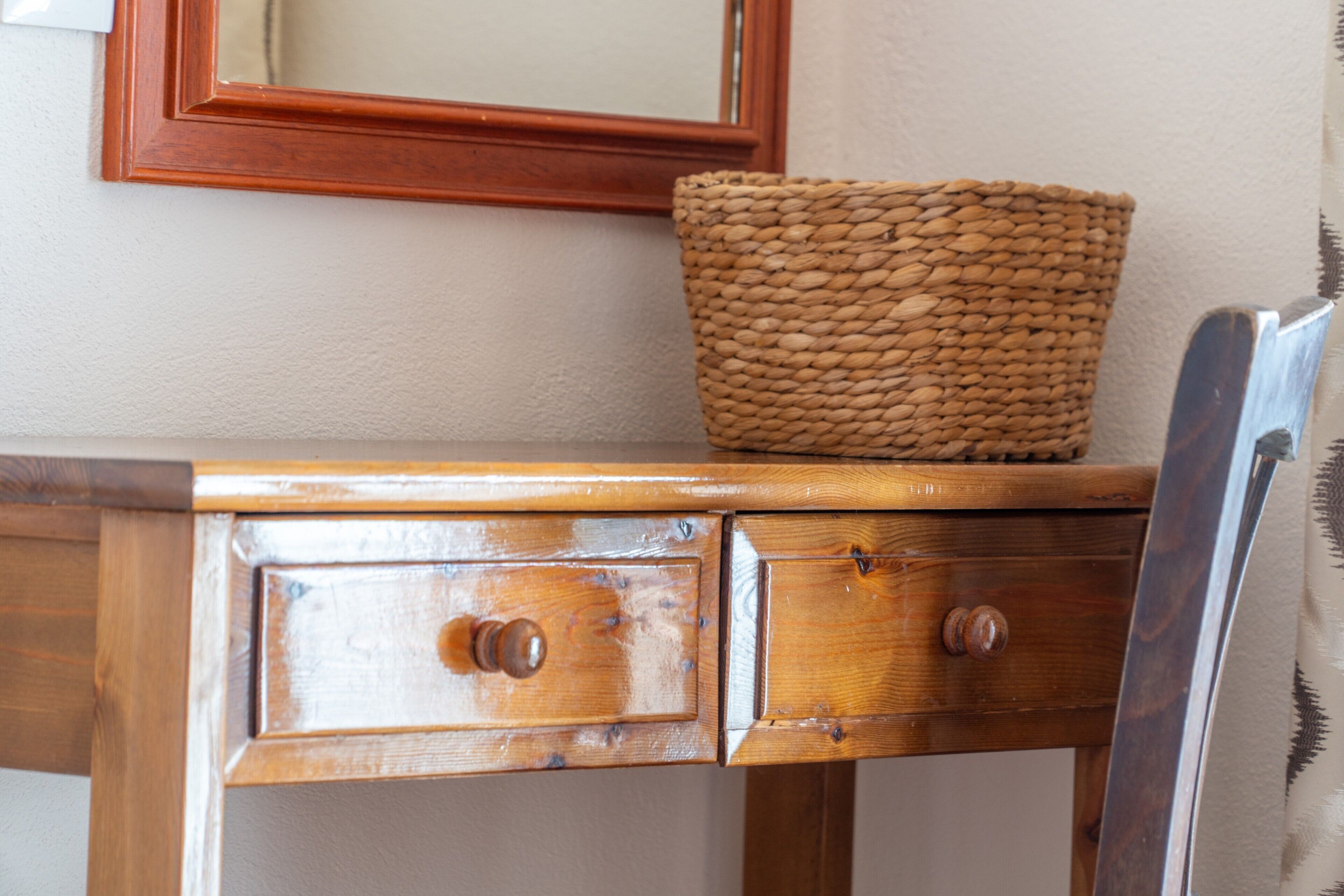 A wooden dresser with two drawers and a wicker basket on top.