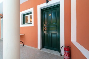 A building entrance with a green door, a window, and a fire extinguisher.