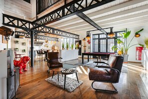 A spacious loft with exposed beams, a dining area, and a kitchen.