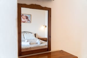 A bedroom with a bed, a nightstand, a wall-mounted picture, and a bedside lamp.