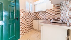 Une cuisine avec une porte verte, un dosseret à carreaux, des armoires blanches et un plan de travail sur lequel se trouve une balance.