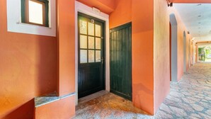 Un couloir avec un sol en pierre, une porte dotée d’une fenêtre et un mur sur lequel est affiché un numéro.