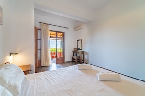 Une chambre à coucher comprenant un lit, une table de chevet, un bureau, une chaise et une fenêtre avec des rideaux.