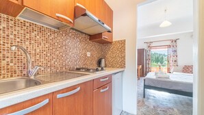 A kitchen with a sink, stove, and cabinets, leading to a bedroom with a bed and window. - Studio "Arianna Studio Ground Floor 5" with Sea View, Shared Pool & Wi-Fi (Corfu)