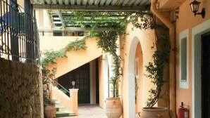 Ein Innenhof mit Steinpflasterung, großen Pflanzkästen und einem überdachten Bereich mit Metallgitter.